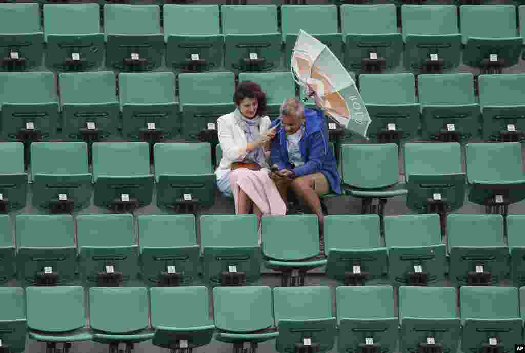 The wind pulls at the umbrella of a spectator as weather conditions suspended the fourth round match between France&#39;s Alize Cornet and Ukraine&#39;s Elina Svitolina at the French Open tennis tournament at Roland Garros stadium in Paris, France.