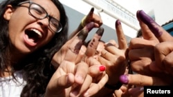 Tunisians show their ink-stained fingers after casting their votes in Tunis, Oct. 26, 2014. 