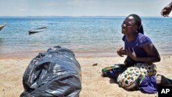 A woman cries beside the body of her sister, a victim of the MV Nyerere passenger ferry, as she awaits transportation for burial on Ukara Island, Tanzania Saturday, Sept. 22, 2018.