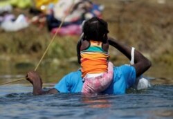 Un migrante con un niño que busca refugio en EE. UU. cruza el río Bravo desde Ciudad Acuña, México hacia Del Rio, Texas, EE. UU., en Ciudad Acuña, México el 22 de septiembre de 2021.