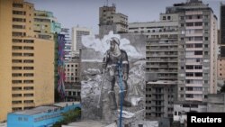 El artista y activista brasileño Mundano trabaja en el mural 'The Forest Brigade' usando pintura hecha con cenizas recolectadas y traídas de incendios en el Amazonas, Pantanal y otros biomas, en Sao Paulo, Brasil, el 14 de octubre de 2021.