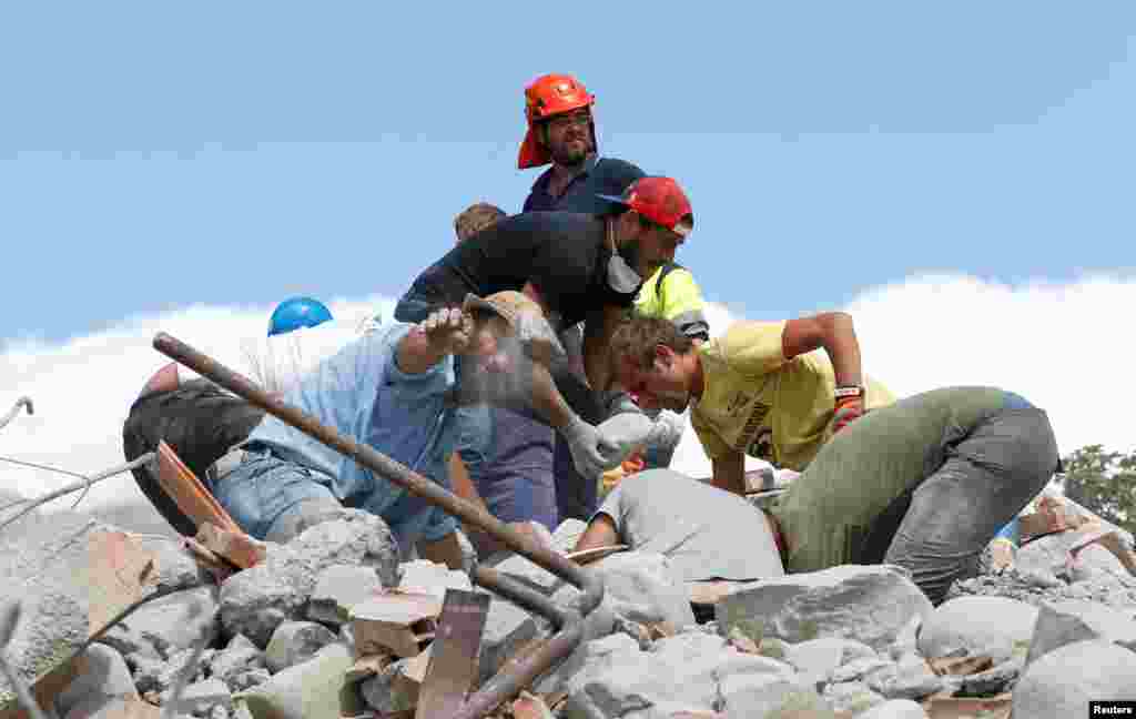 Petugas menggali puing-puing bangunan di Amatrice, Italia (25/8). (Reuters/Ciro de Luca)
