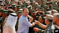 FILE - President George H.W. Bush is greeted by Saudi troops and others as he arrives in Dhahran, Saudi Arabia, for a Thanksgiving visit, Nov. 22, 1990. 