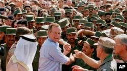 President George H.W. Bush is greeted by Saudi troops and others as he arrives in Dhahran, Saudi Arabia, for a Thanksgiving visit, Nov. 22, 1990. Bush died at the age of 94 on Friday, Nov. 30, 2018, about eight months after the death of his wife, Barbara Bush.