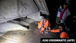 Des habitants et des sauveteurs inspectent une zone couverte de cendres volcaniques dans le village de Sumber Wuluh, en Indonésie, le 5 décembre 2021.