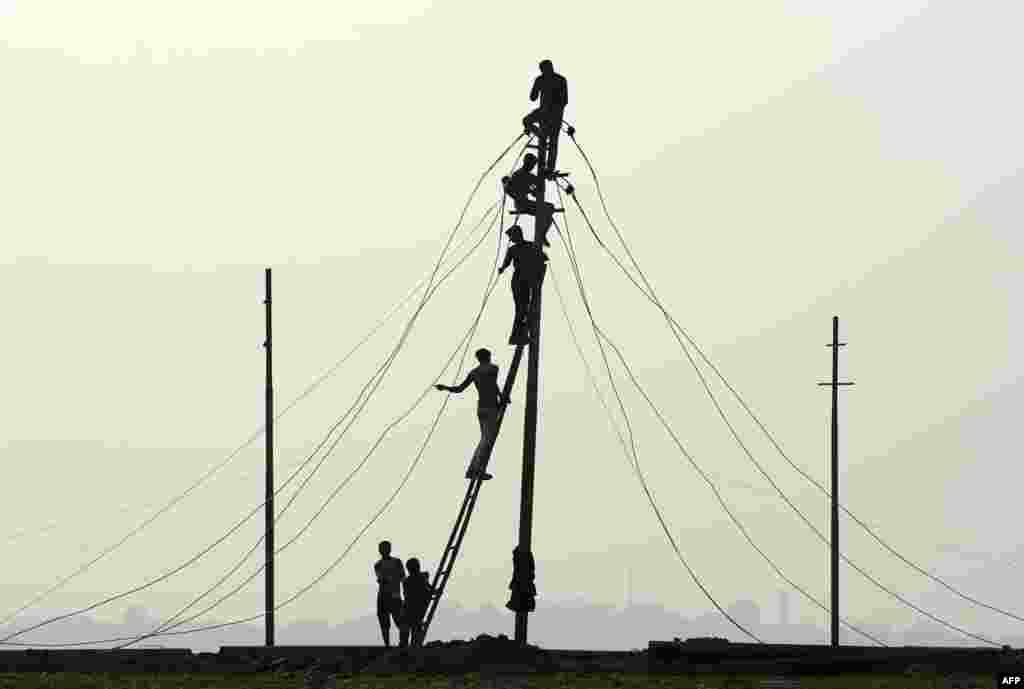Workers install electricity cables on the banks of the river Ganges in preparation for the annual Hindu religious fair of Magh Mela in Allahabad, India.
