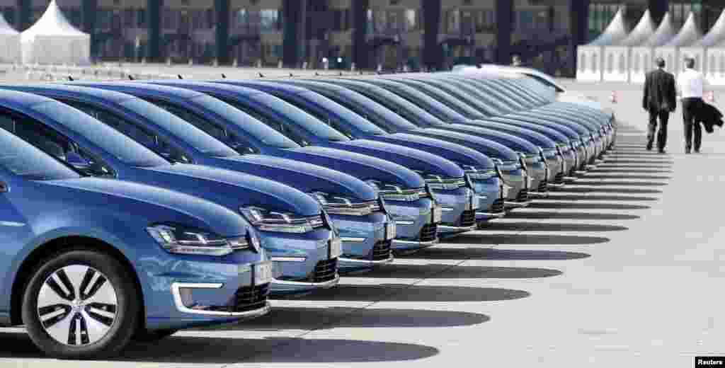 People walk past a row of Volkswagen e-Golf cars during the company&#39;s annual news conference in Berlin, Germany.