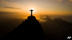 The sun rises behind the Christ the Redeemer statue, above the Guanabara bay in Rio de Janeiro, Brazil, July 19, 2016. 