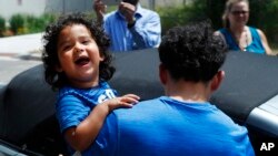 Ever Reyes Mejía, de Honduras, lleva a su hijo hasta un vehículo, luego de ser reunidos y liberado la agencia de Inmigración y Control de Aduanas de EE.UU. (ICE), en Grand Rapid, Michigan, el martes 10 de julio de 2018. Dos niños y una niña hondureños que estaban en casas de acogida en Grand Rapids fueron reunidos con sus padres después de haber sido separados en la frontera de EE.UU. con México hace unos tres meses. (AP Photo/Paul Sancya)