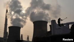 FILE - A laborer works near cooling towers of a power plant on the outskirts of Xiangfan, Hubei province, Nov. 24, 2010.