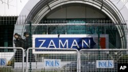 FILE - Riot police officers walk by the headquarters of Zaman newspaper in Istanbul, Turkey, March 6, 2016. 