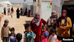 FILE - Syrian refugees look out at Al Zaatari refugee camp in the Jordanian city of Mafraq, near the border with Syria March 28, 2017.