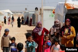 FILE - Syrian refugees stand at Al Zaatari refugee camp in the Jordanian city of Mafraq, near the border with Syria March 28, 2017.