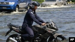 An Air Force officer rides his motorcycle through a flooded Paholyothin road near Don Muang airport in Bangkok, Thailand, October 25, 2011.