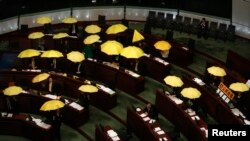 Para anggota parlemen pro-demokrasi membuka payung kuning - simbol solidaritas mereka - saat berlangsungnya rapat dewan legislatif di Hong Kong (7/1).