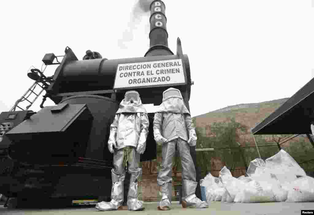 Anti-narcotic workers wait as bags containing cocaine are burnt during a drug incineration in Lima, Peru.