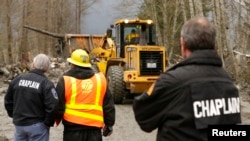 Washington State Police chaplains watch as workers dig through debris left following a mudslide, near Oso, Washington, March 25, 2014.