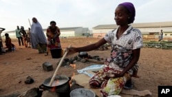 FILE - An unidentified woman who fled her home following an attack by Islamist militants, in Mubi, prepares a meal at the camp for internally displaced people in Yola, Nigeria.