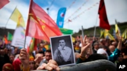 FILE - A woman holds a photograph of former co-leader of pro-Kurdish Peoples' Democratic Party, or HDP, Selahattin Demirtas, during the Newroz celebrations, marking the start of spring, in Istanbul, March 21, 2018.