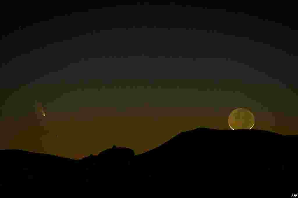 Comet PanSTARRS (L) is seen with a one-day old crescent moon as both set over the Very Large Array radio telescope antenna dishes March 12, 2013 near Magdalena, New Mexico, USA.