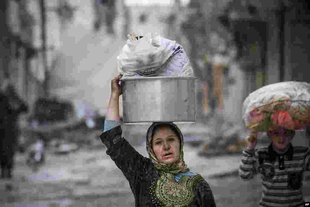 A woman and girl carry their belongings after their home was damaged in fighting between Free Syrian Army fighters and government forces in Aleppo, Syria, December 11, 2012.
