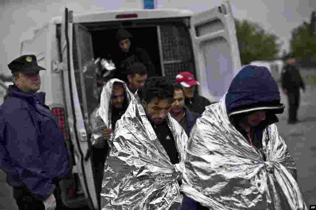 People get out of a police van as they are being dropped off to a reception center for migrants and refugees in Opatovac, Croatia.