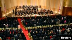 The U.S. and North Korean flags hang at the side of the stage and the audience stands while Music Director Lorin Maazel conducts the New York Philharmonic playing the U.S. national anthem before the start of their concert at the Grand Theatre in the Pyongyang, North Korea, Feb. 26, 2008.