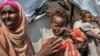 FILE - Nasteho Hassan Mohyadin, 3, and her mother Farhid Ali Mohamed sit outside their small makeshift tent in a camp for those displaced by 2012 famine or by conflict, in Mogadishu, Somalia.