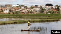 FILE - A man travels in a boat to fish in a pond in the outskirts of the capital Antananarivo, Madagascar.