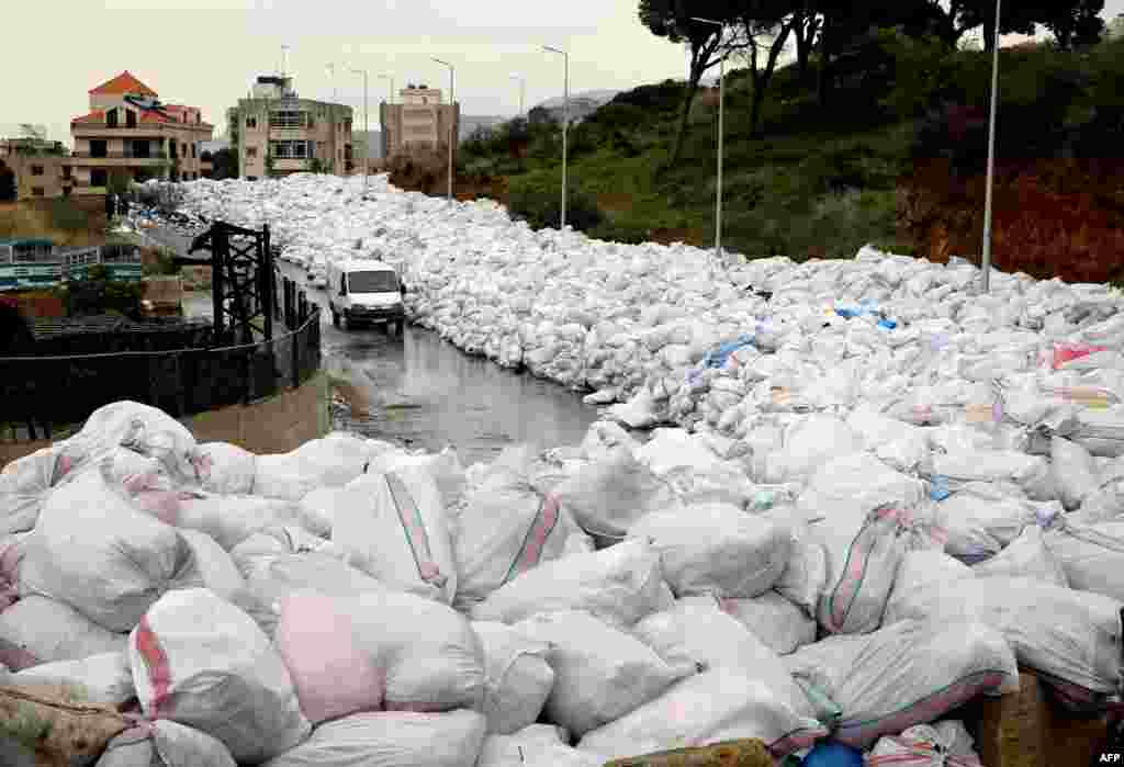 A van drives past piles of wrapped garbage blocking a newly-opened road in the town of Jdeideh northeast of Beirut, Lebanon.