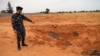 Un membre des forces de sécurité fidèles au GNA pointe vers une fosse commune à Tarhouna, en Libye, le 11 juin 2020.