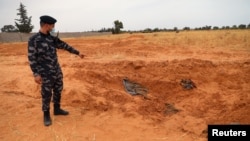 A member of security forces loyal to Libya's internationally recognized government points to a mass grave, according to Libya's Internationally recognized government officials, in Tarhouna city, Libya, June 11, 2020.