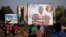 People ride motorcycles past a billboard for presidential candidate Benewende Sankara in Ouagadougou, Burkina Faso, Nov. 28, 2015. The billboard reads, "Vote Benewende Sankara, the insurgents' candidate."