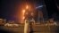 Two Emirati officials watch a high-rise building as a fire spreads up the side of the building in Ajman, United Arab Emirates, March 29, 2016. 