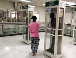 Seorang pengunjung mengamati jazad pembunuh berantai Si Ouey (kanan) yang diawetkan dan dipajang tegak dalam kotak kaca di Museum Rumah Sakit Siriraj Forensik, di Bangkok, Thailand, 17 Mei 2019.