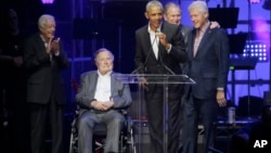 Former President Barack Obama, speaks as fellow former Presidents, from left, Jimmy Carter, George H.W. Bush, George W. Bush, and Bill Clinton look on during a hurricanes relief concert in College Station, Texas, Oct. 21, 2017. 