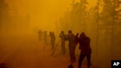 FILE - Volunteers pause while working at the scene of a forest fire near Kyuyorelyakh village at Gorny Ulus area west of Yakutsk, in Russia, Aug. 7, 2021. 