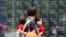 People walk by an electronic stock board of a securities firm in Tokyo, May 13, 2013.