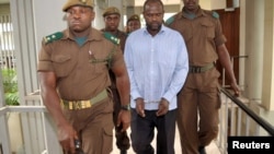 Le chef des rebelles ougandais, Jamil Mukulu, est escorté par des gardiens de la prison tanzanienne devant le tribunal d'instance à Dar es-Salaam, le 22 mai 2015.