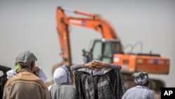 Relatives of crash victims mourn as a mechanical digger operates at the scene where the Ethiopian Airlines Boeing 737 Max 8 crashed shortly after takeoff on Sunday killing all 157 on board, near Bishoftu, southeast of Addis Ababa, in Ethiopia, March 14, 2019.