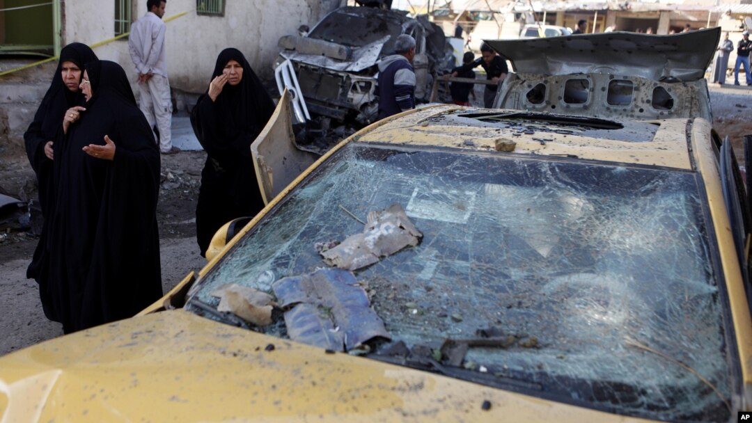 Warga setempat melewati tempat meledaknya bom pinggir jalan di kota Hillah, Irak. (Foto: AP)