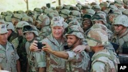 FILE - U.S. President George H. Bush holds a camera at arm's length for a self-portrait with Marines at Baidoa's airport, Jan. 1, 1993 in Baidoa. 