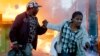 A couple run past burning shops during clashes in Nairobi, Kenya, Oct. 27, 2017.