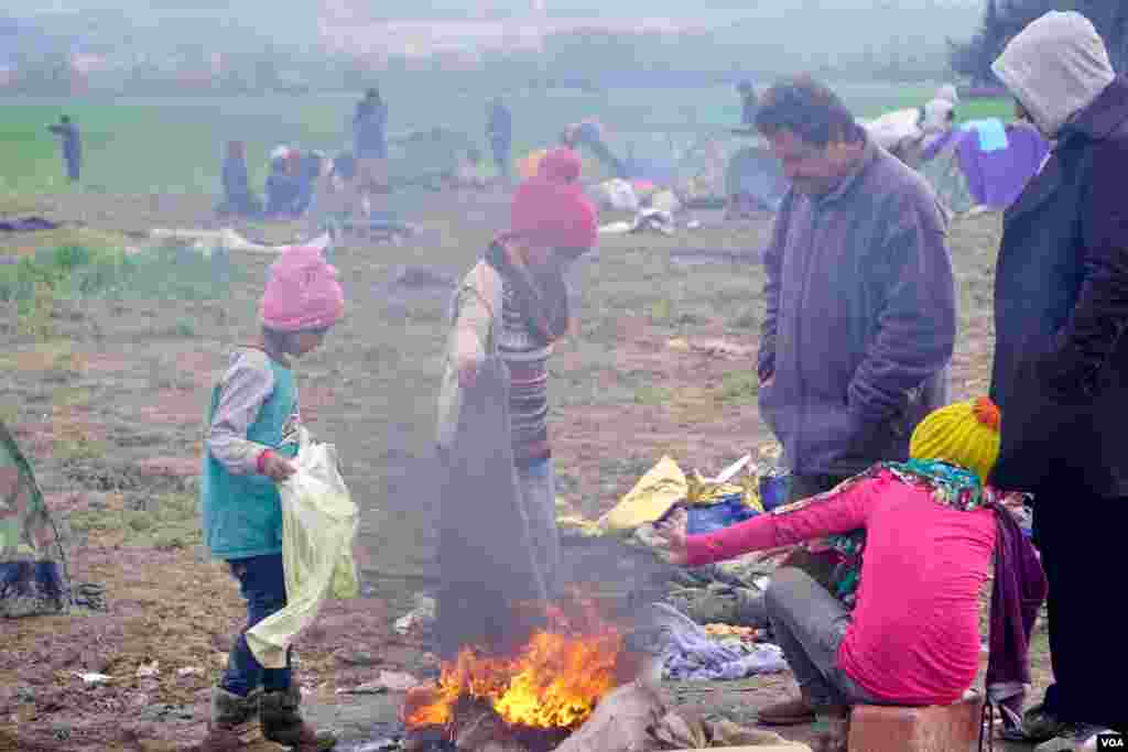 Para pengungsi di kamp Idomeni menghangatkan diri dengan membakar selimut tua. (VOA/Jamie Dettmer)