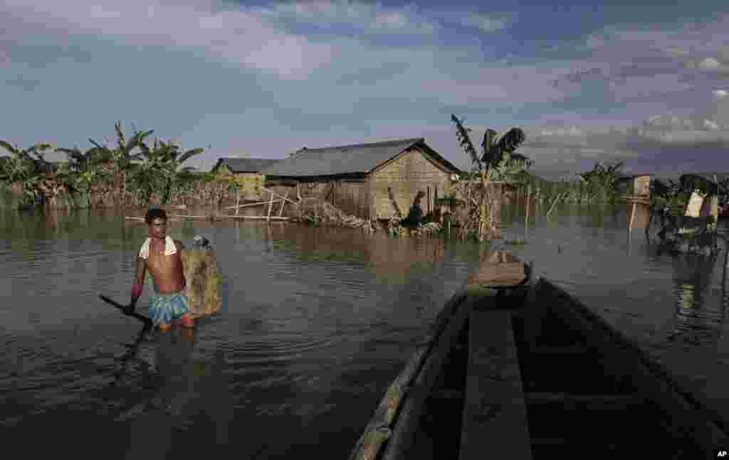 An Indian villager wades through flood waters at Gagalmari village in Assam state, India, July 2, 2012. 