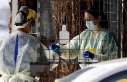 FILE - Medical staff prepare to take a COVID-19 tests at a drive through community based assessment center in Christchurch, New Zealand, Aug. 13, 2020.