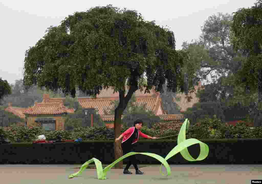 A woman exercises with a ribbon during a morning exercise session at Jingshan Park in Beijing, China.