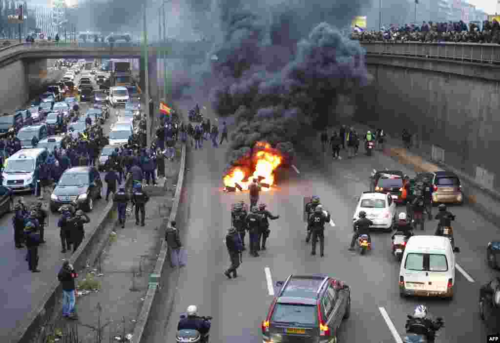 Anti-riot police arrive as taxi drivers block the traffic with a fire during a demonstration against the VTC (transport vehicle with chauffeur) on the ring road (peripherique) at porte Maillot in Paris, France.