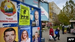 FILE - Pedestrians pass by electoral posters with candidates for the presidential and parliamentary elections in Bucharest, Nov. 22, 2024. Romania's constitutional court announced on Dec. 6, 2024, that it was canceling the presidential election.