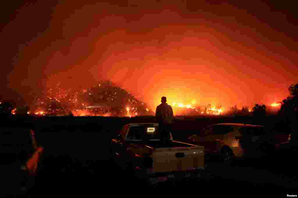 A person looks on as smoke and flames billow from the Mountain Fire in Santa Paula, California, Nov. 6, 2024. 